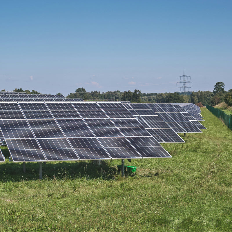 Row of solar panels in a field with a clear blue sky